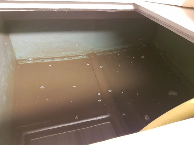 Visible sediment and deposits inside a cold water storage tank prior to scheduled cleaning works.